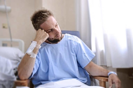 A despondent man sits alone in a hospital chair.