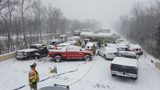 Snowy highway pileup with various emergency responders on scene.