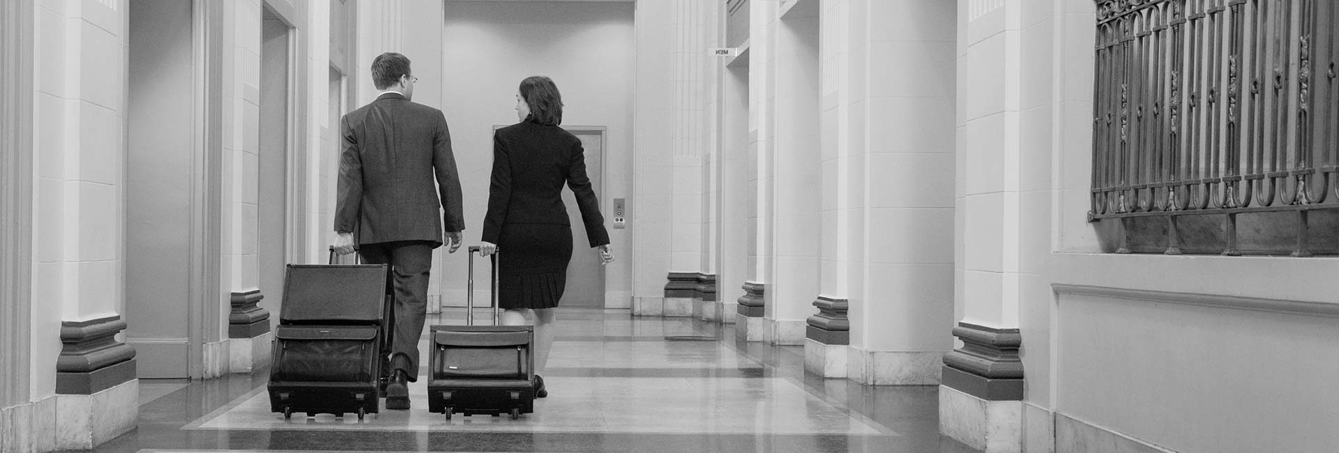 Attorneys with luggage walking down courtroom hallway
